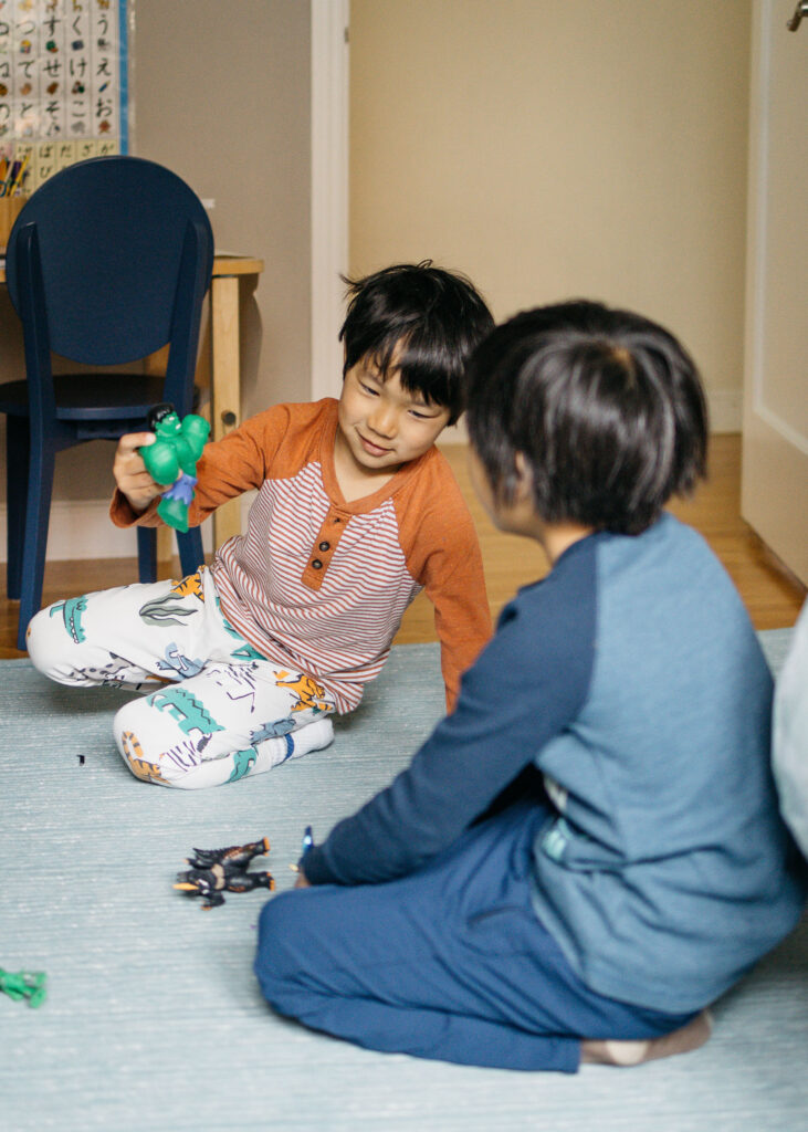 brothers playing with action figures in the bedroom.