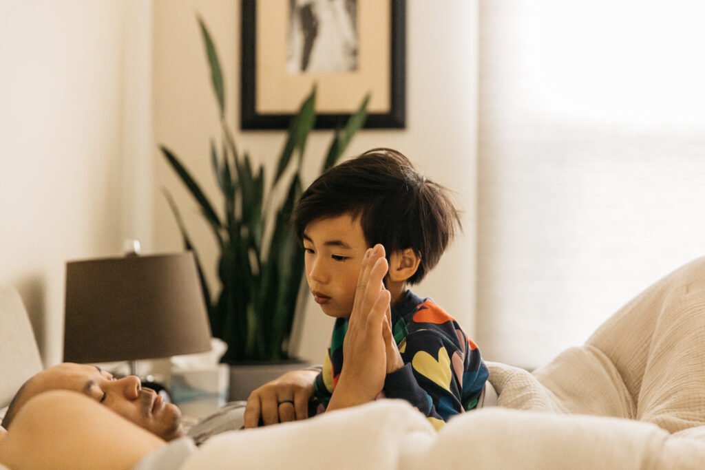 boy giving dad a high five in bed.