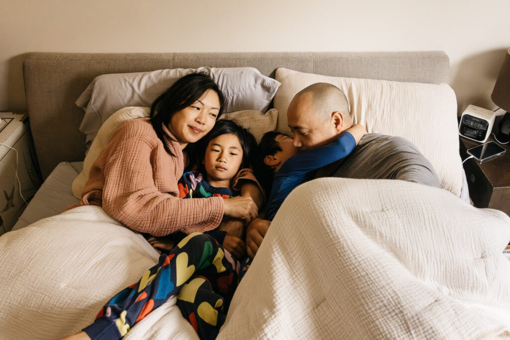 family snuggling in bed in the morning during a day in the life photo session.