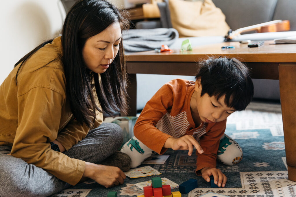 mom showing son how to play with blocks during an in-home photo session in san francisco.