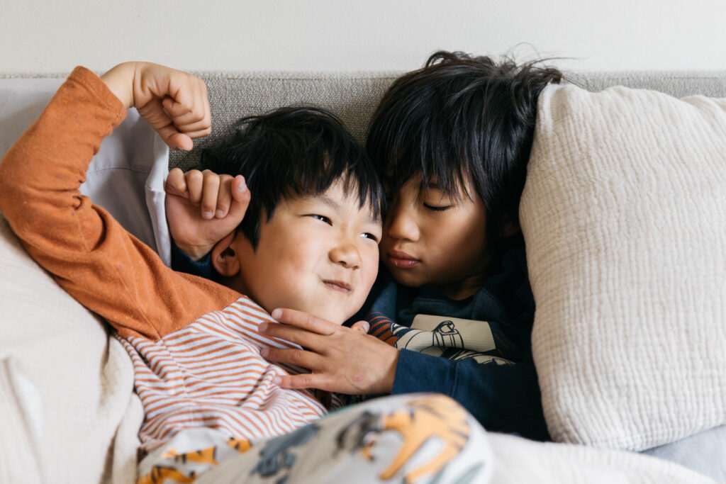 sibling brothers wrestling in bed during a family photo session.
