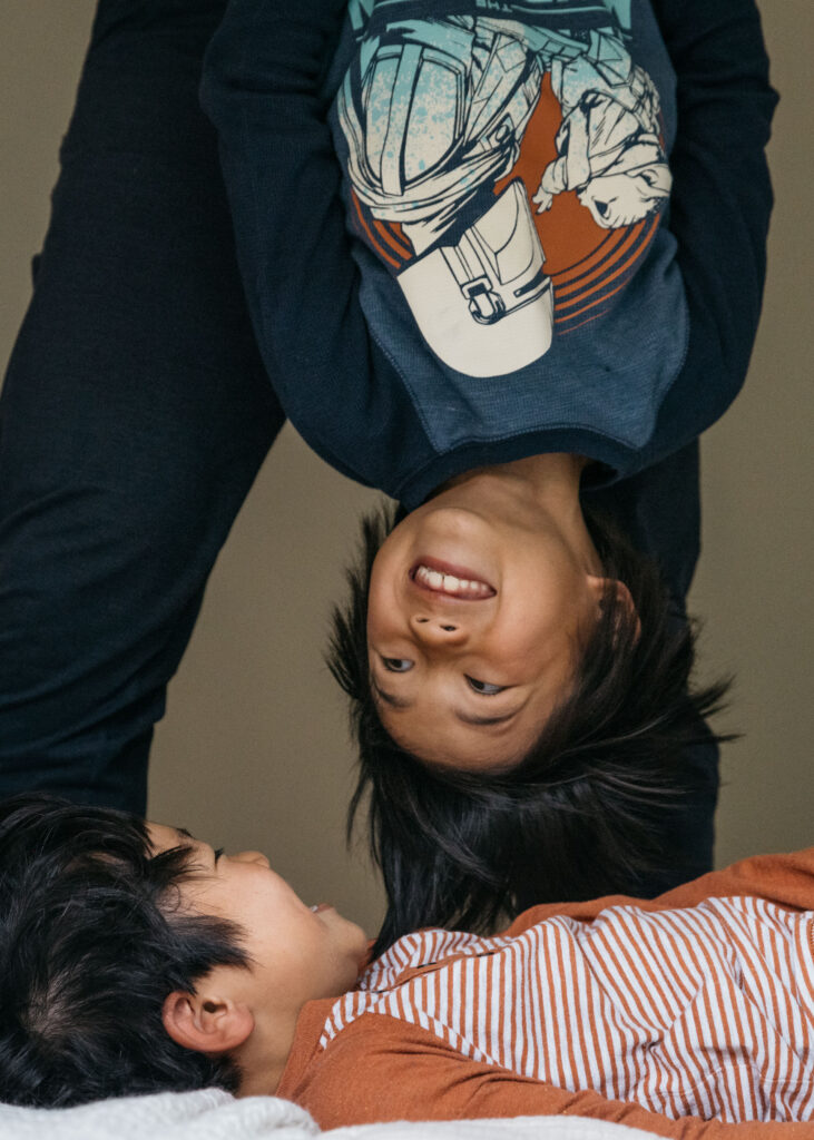 brothers hanging upside in bed during a family photo session in san francisco.