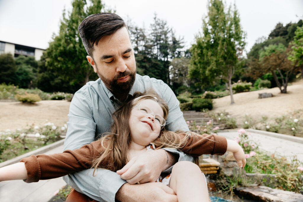 IMG_3828-Edit-Oakland-Family-Photographer-Carmen-Dunham-Photography Dad hugging daughter during a family photo session at the Oakland Rose Garden.