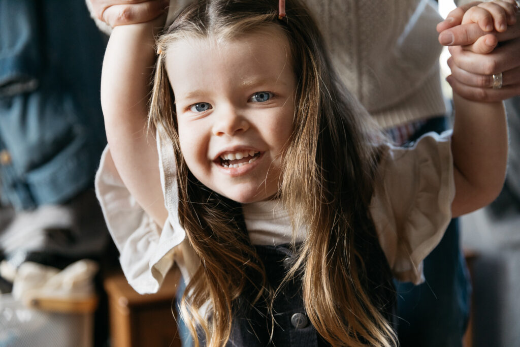 young girl holding dad's hand during an in-home family photo session.