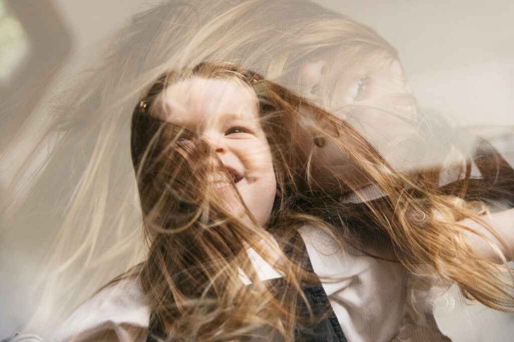 toddler girl dancing at home during a family photo session in oakland.