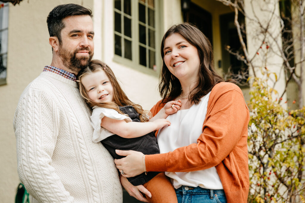 family smiling in front of their home in oakland.