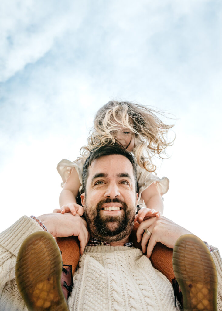 dad carrying young girl on his shoulders