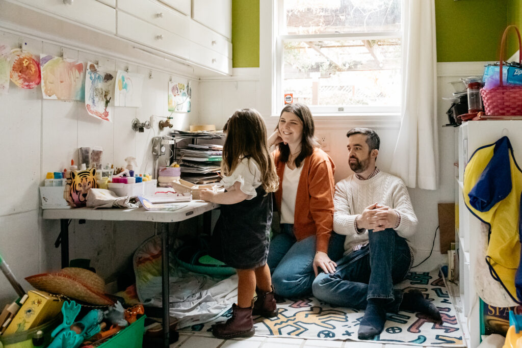 parents watching their young daughter drawing in her art room during an in-home photo session in oakland.