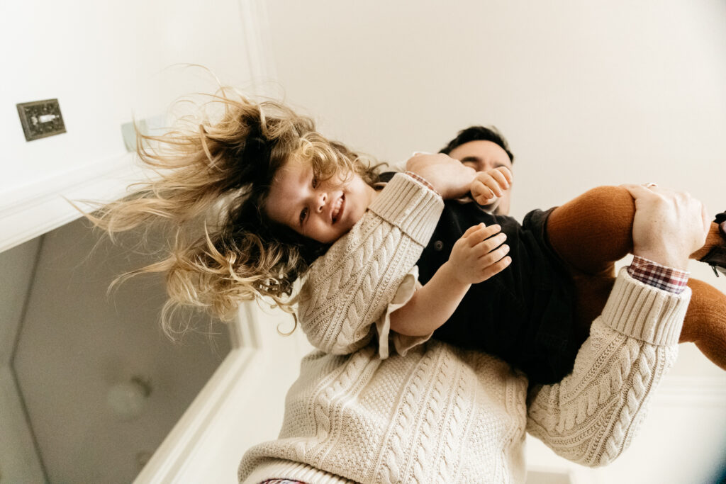 dad carrying daughter upside down on his shoulders in the kitchen.