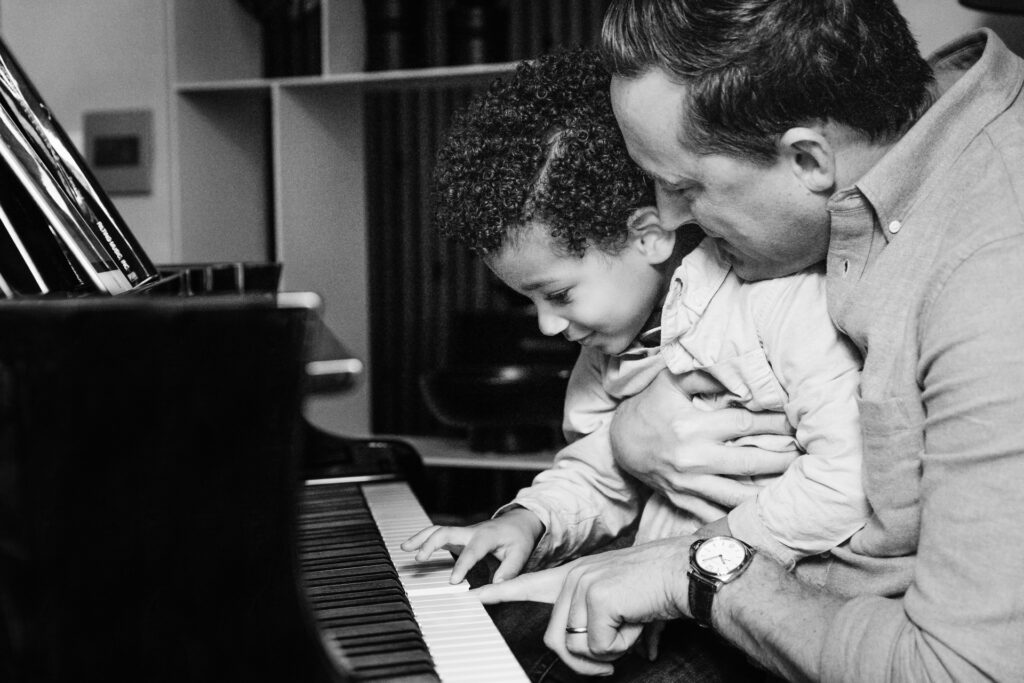 dad showing his toddler son the keys on the piano.