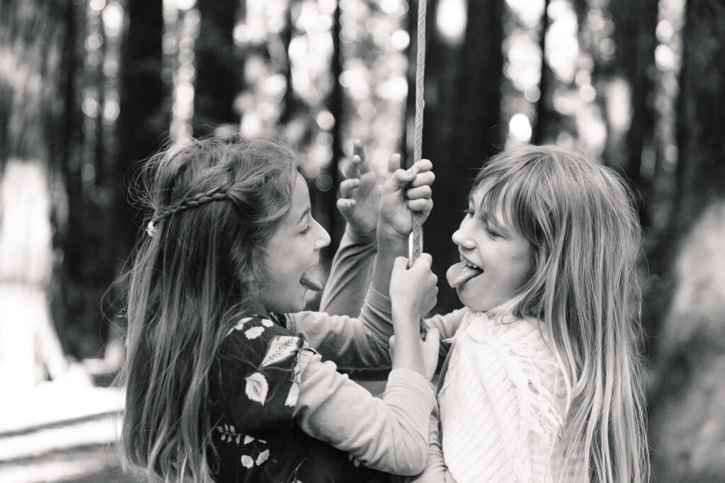 IMG_6580-Oakland-Joaquin-Miller-Family-Photography-Session-Carmen-Dunham-Photography Sibling sisters being silly and sticking their tongues out on a rope swing at Joaquin Miller Park.