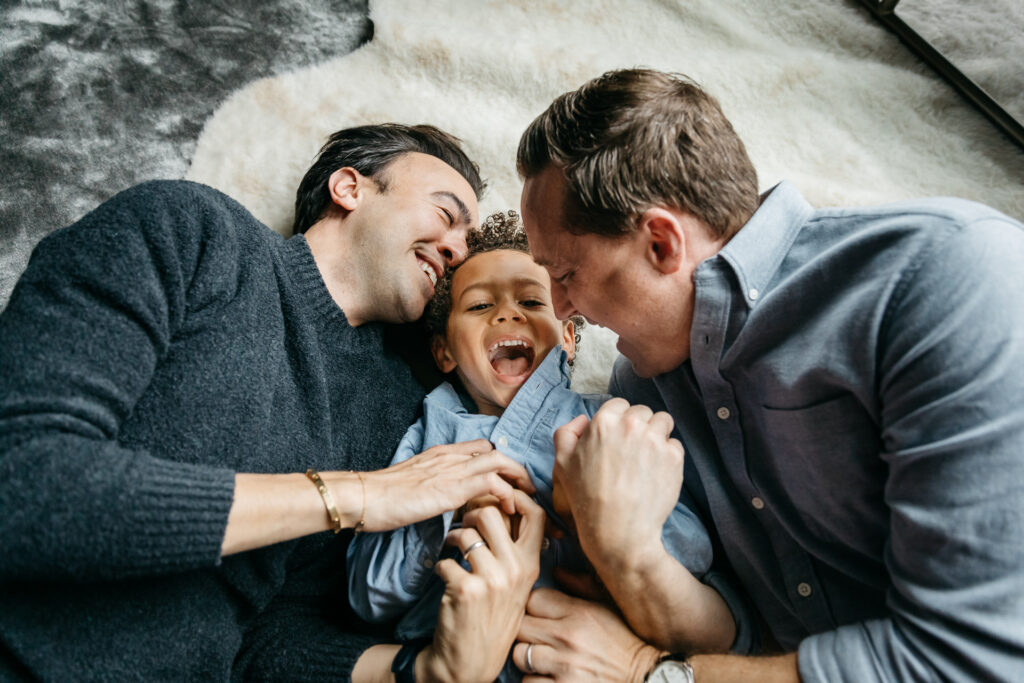 dads snuggling with toddler son on the living room floor during an in-home photo session in san francisco.