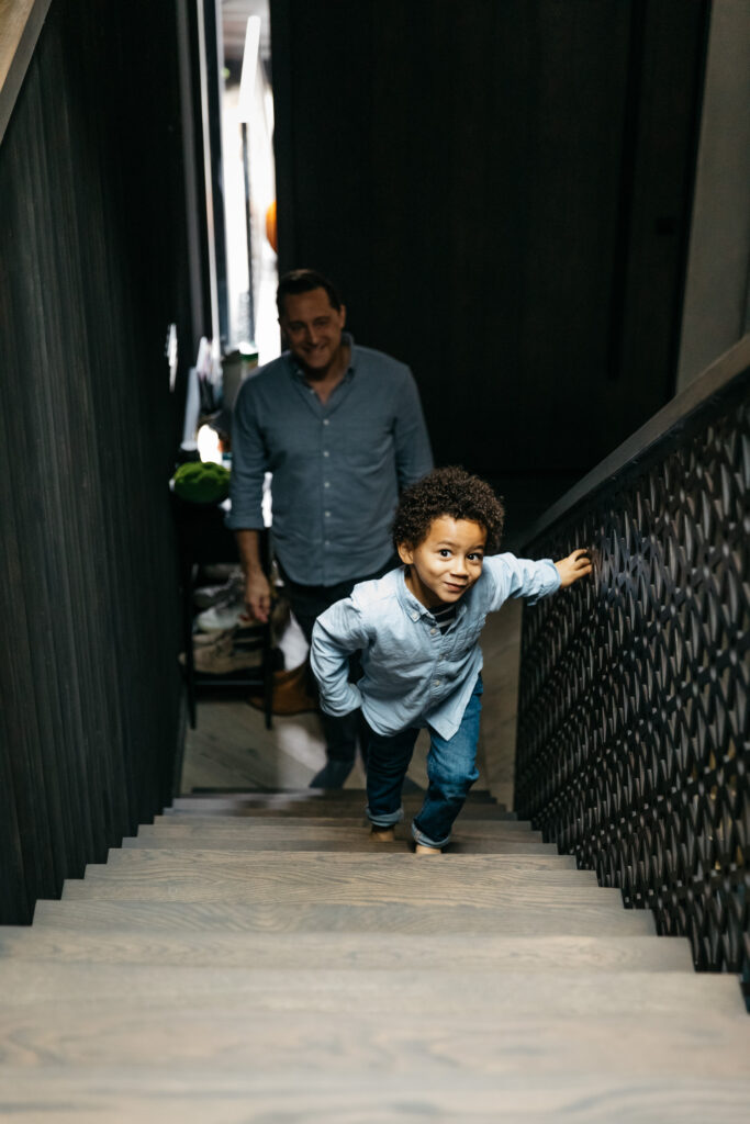 toddler boy climbing the stairs with dad.