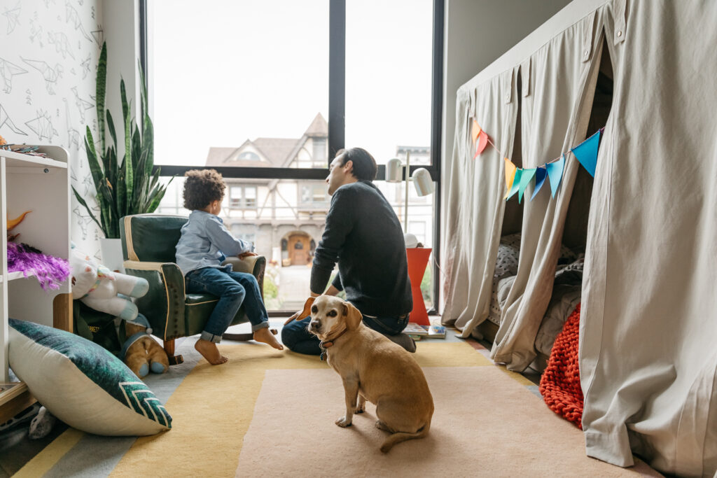 dad and toddler son looking out the bedroom window.