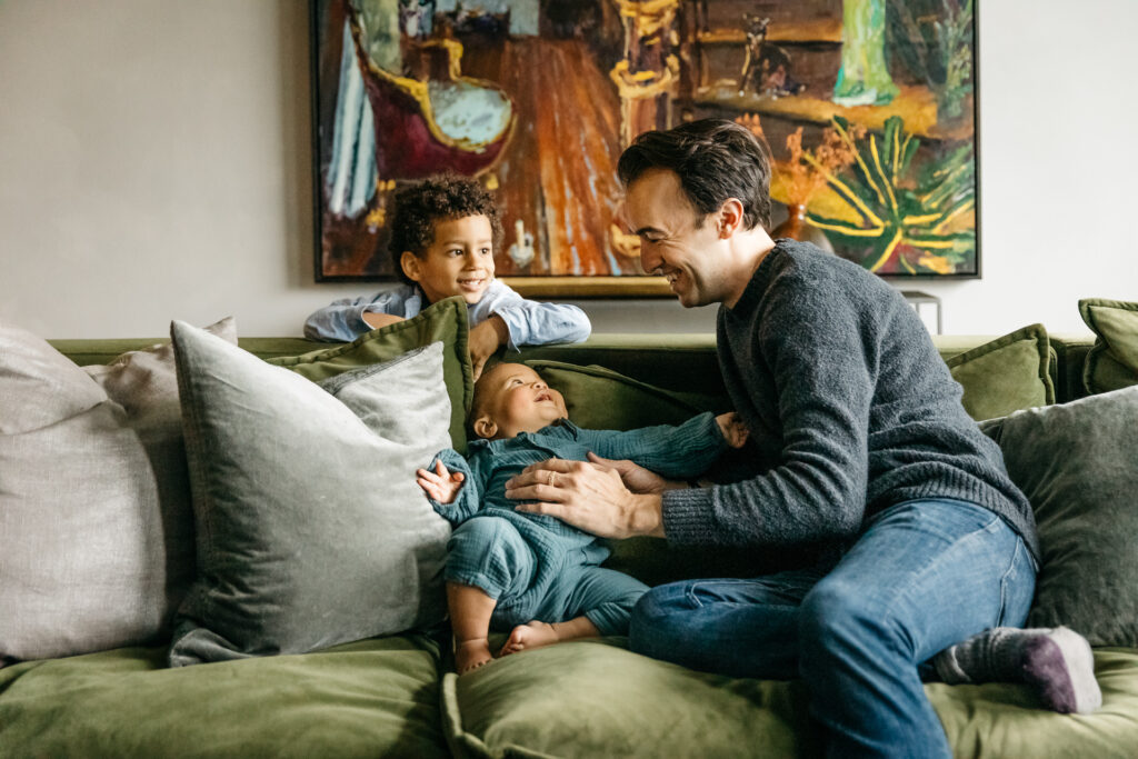 dad playing with son and daughter on the living room sofa