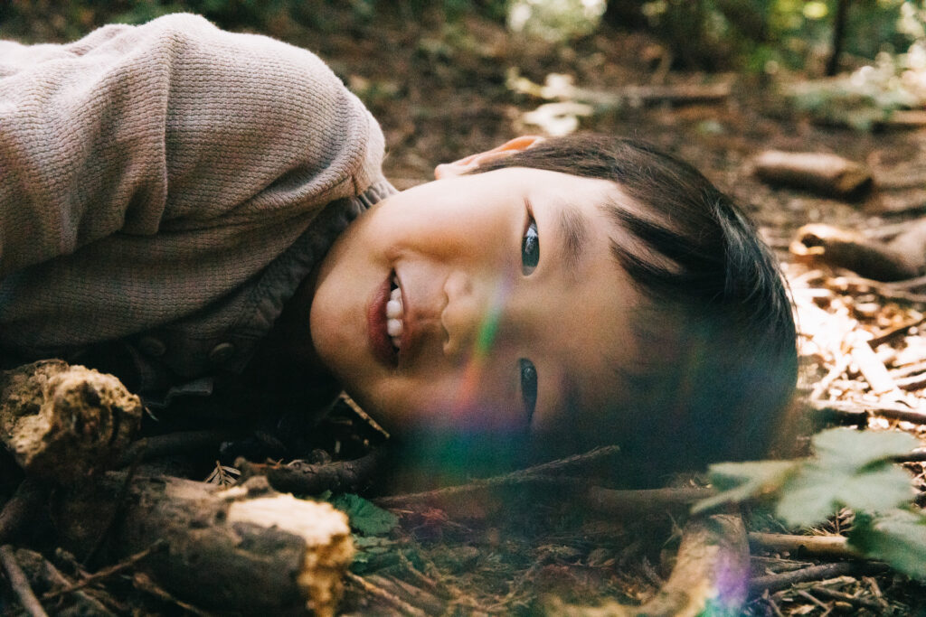 IMG_9407-Oakland-Joaquin-Miller-Family-Photography-Session-Carmen-Dunham-Photography Young boy laying down on the bark in the redwood grove of Joaquin Miller Park.