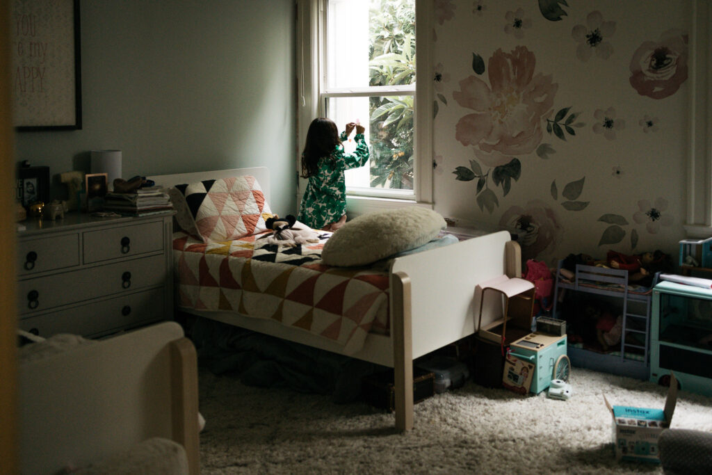 Young girl is putting decals onto her bedroom window.