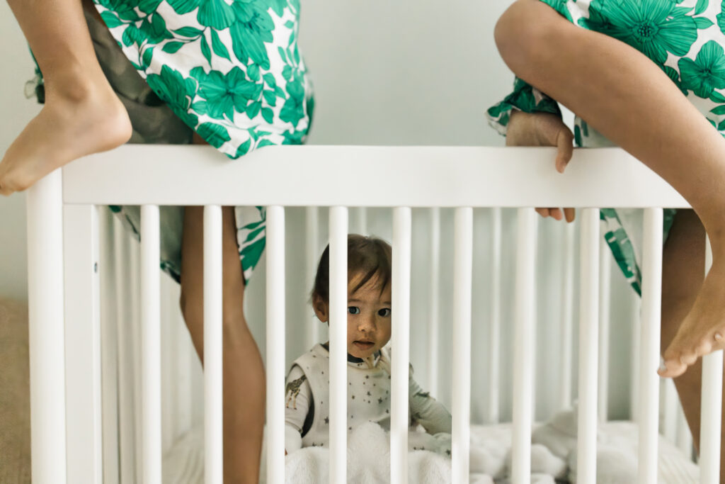 Older sisters are climbing into brother's crib as he wakes from his nap.