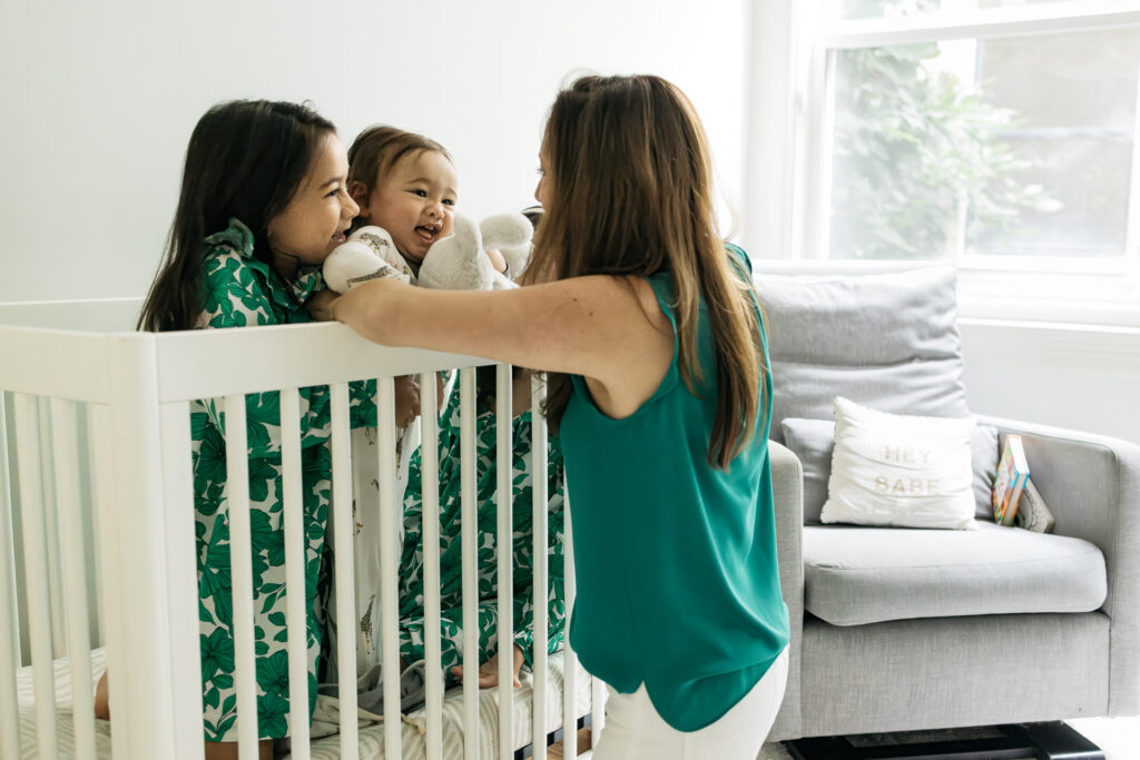 Mother and older siblings greets the waking baby from his nap.