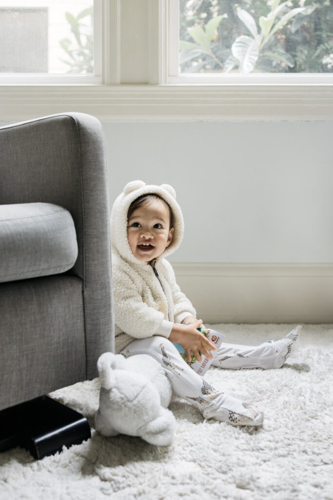 Young boy is laughing and playing with a book in the nursery.