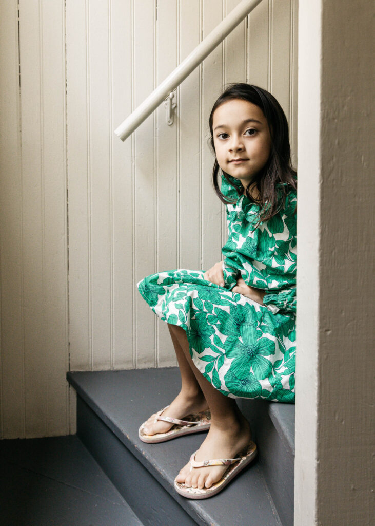 Young girl is sitting on the back stairs of her apartment building.