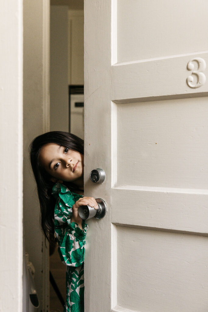 Young girl is peaking out of her backdoor.