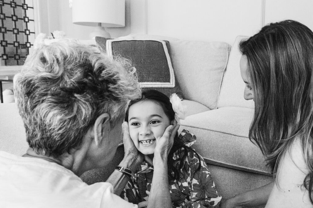 Grandma sweetly holds her granddaughter's cheeks with both hands.