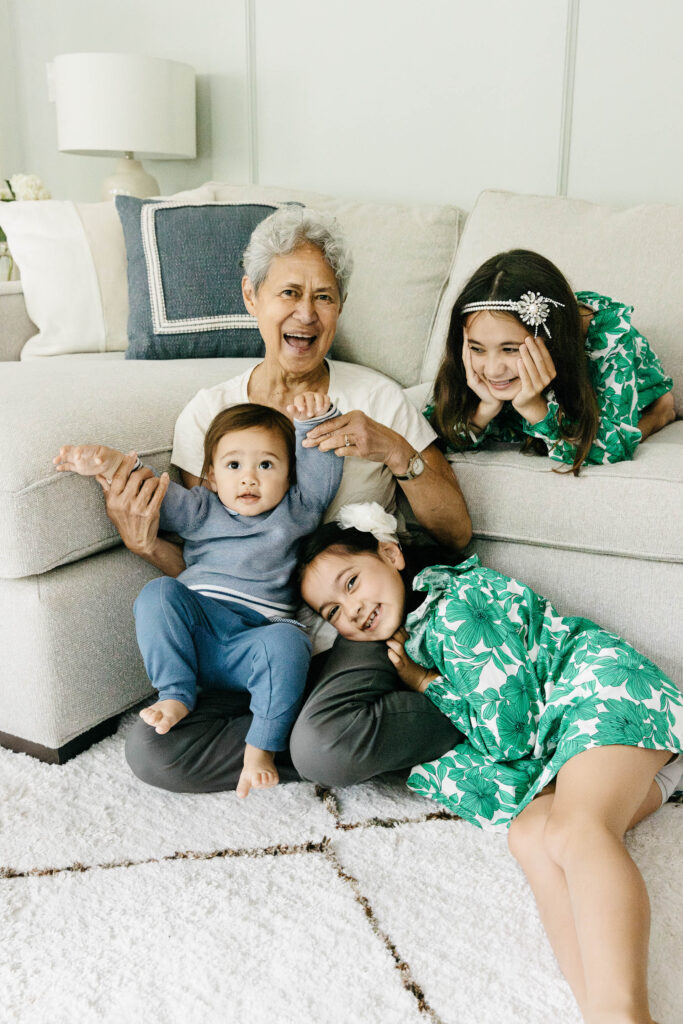 Grandma is playing with her grandkids near the living room sofa.