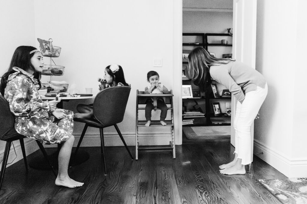Mom is engaging with toddler son as he eats from his highchair.