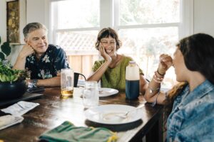 Family laughing and having breakfast together at the kitchen table.
