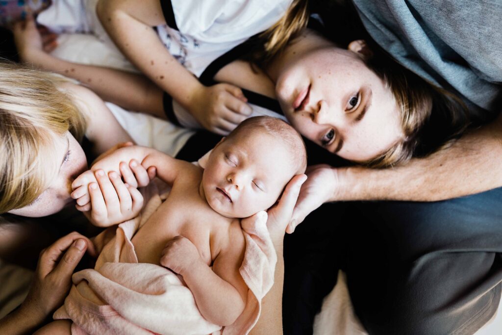 baby girl being held by family on bed at home