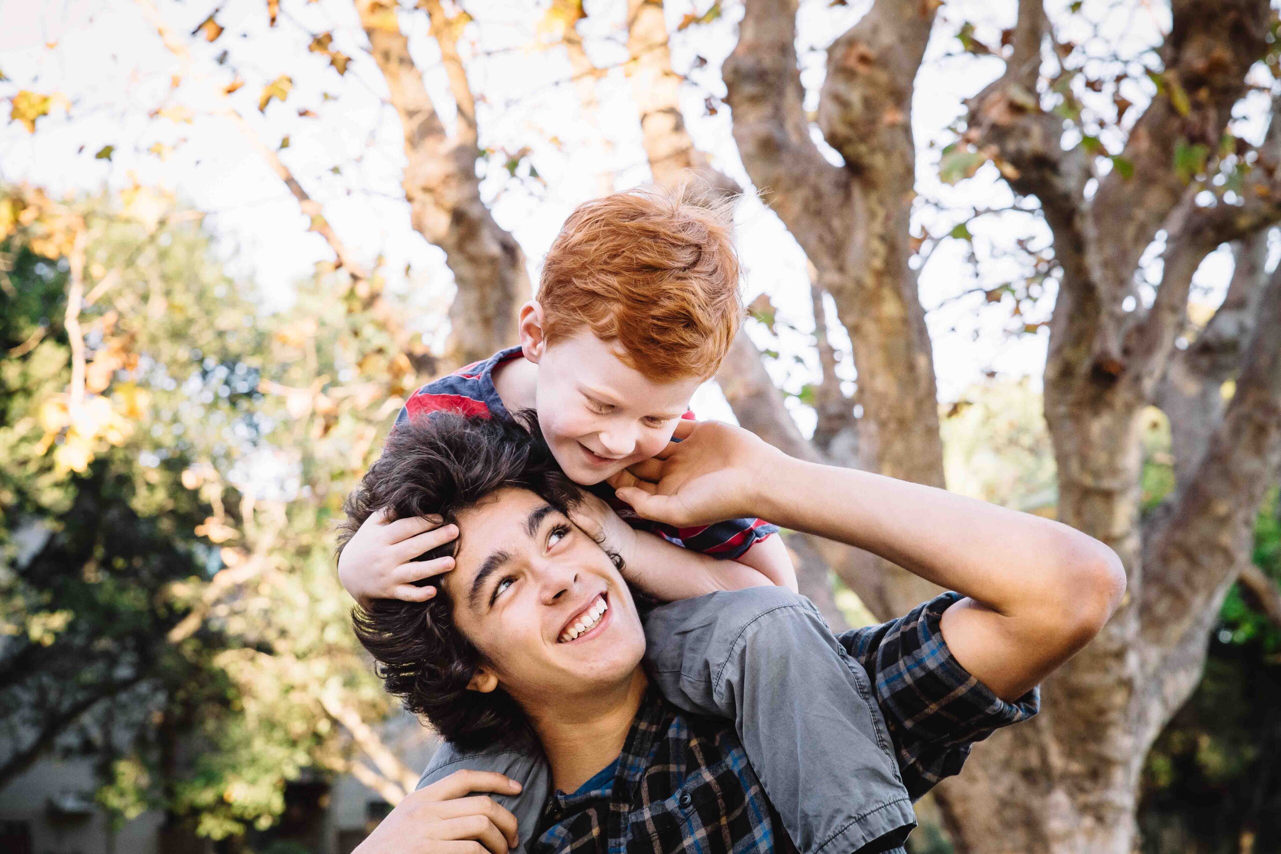 teen boy holding younger sibling on his shoulders