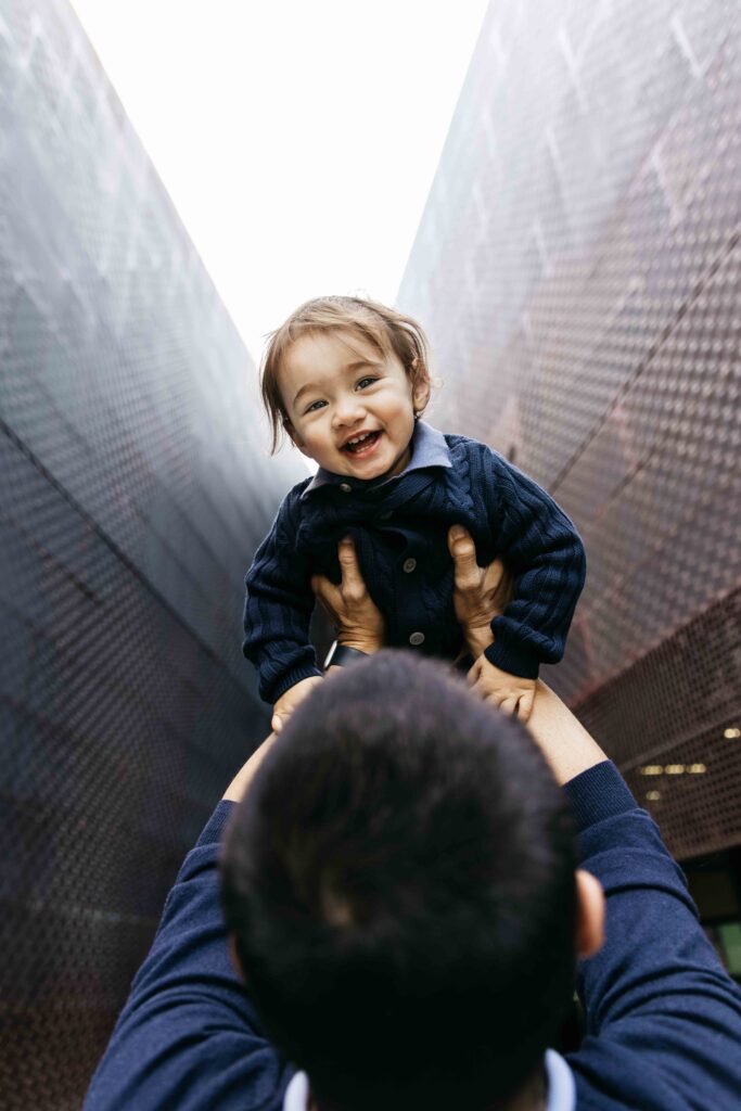 Dad holding toddler son high in the air