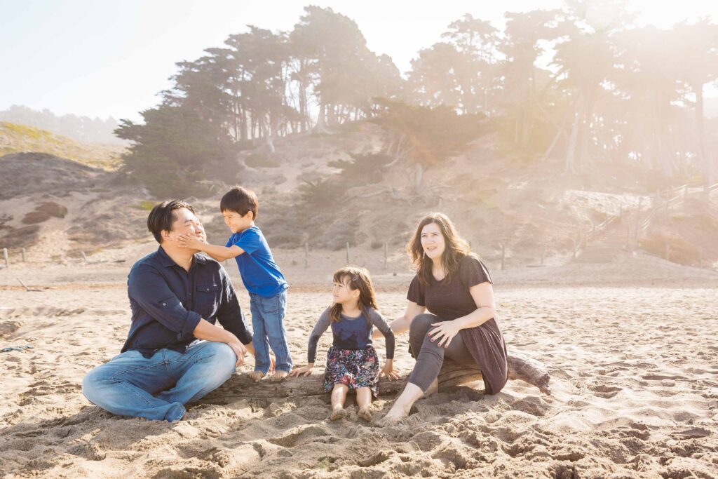Family sitting on a log at Baker Beach.