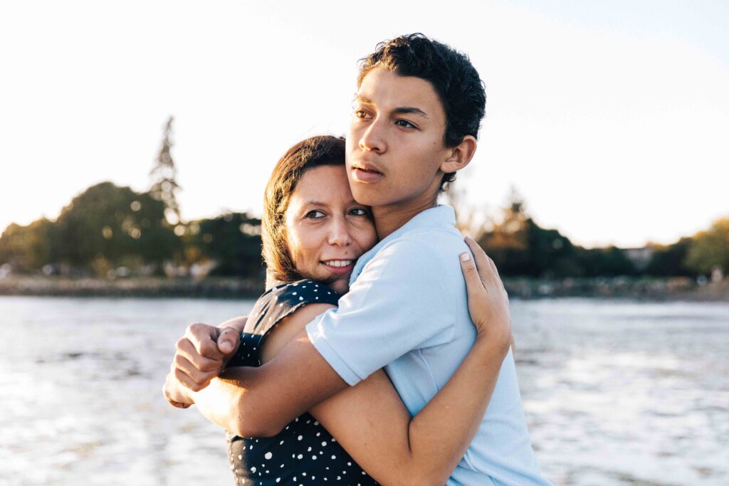 teen holding his mom at the beach