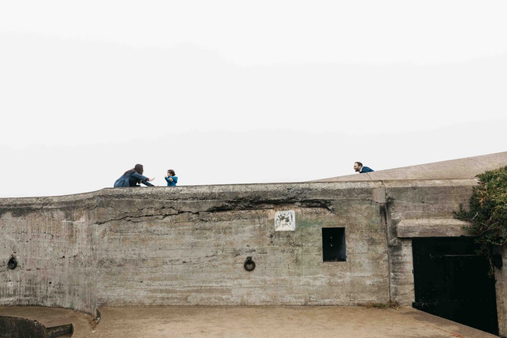 Mom, dad, and young daughter are playing at Battery Chamberlin.