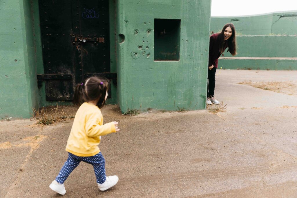 Mom and daughter are playing hide and go seek during a family photo session.