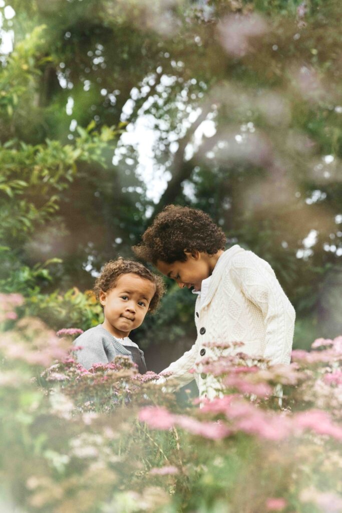 Brother and sister are playing among the blooming flowers during a family photo session.