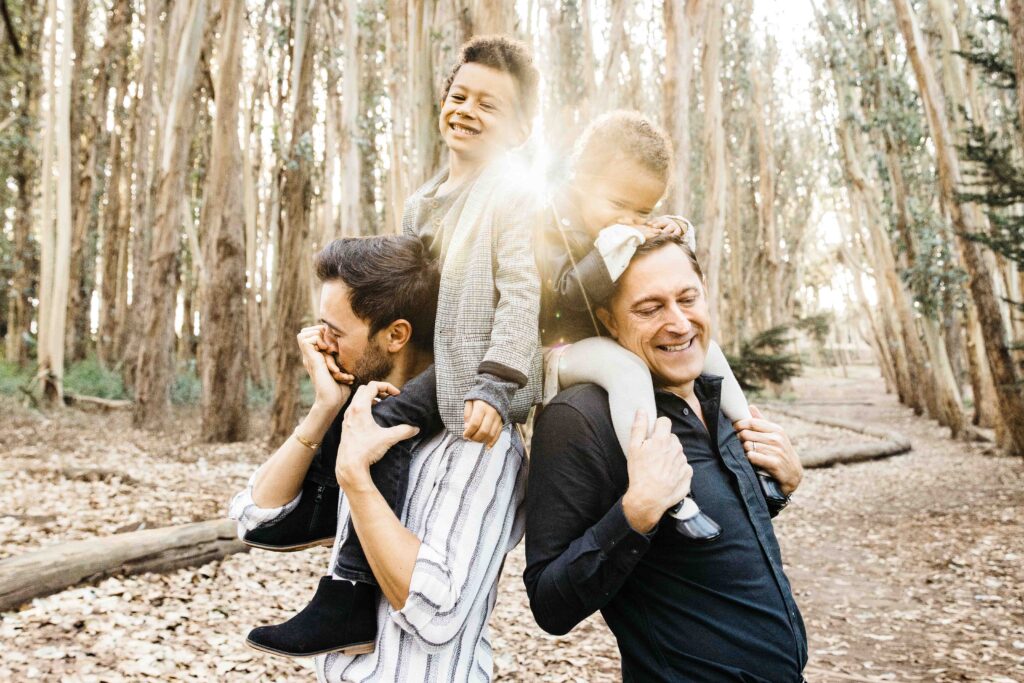 Dads carrying their young kids on their shoulders during a family photo session.