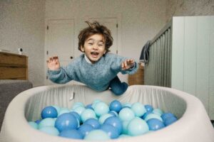 Toddler Boy gleefully jumping into a ball pit at home during a family photo session in San Francisco.