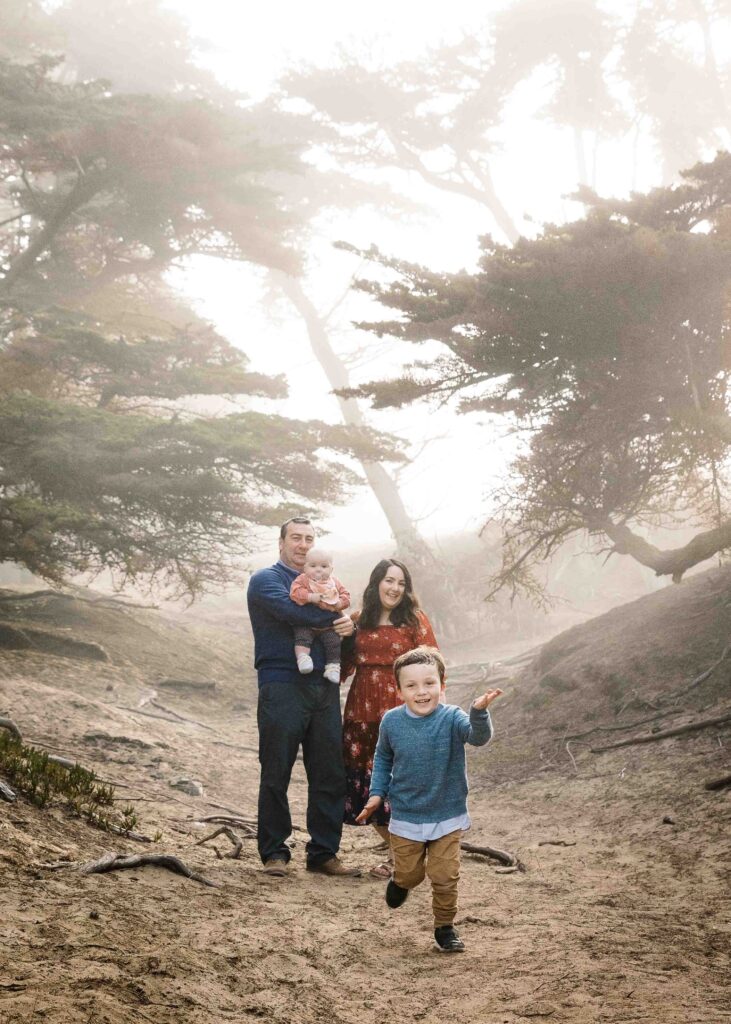 Family are hiking along the cypress trees near Baker Beach.