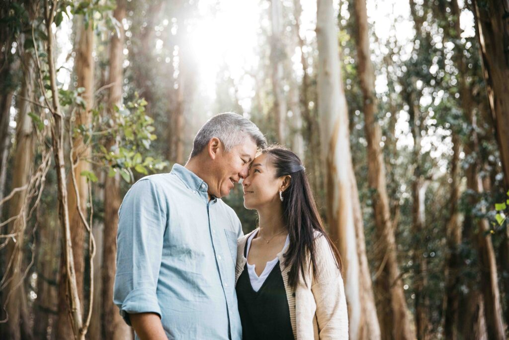 Mom and dad are touching foreheads and having a tender moment during a family photo session.