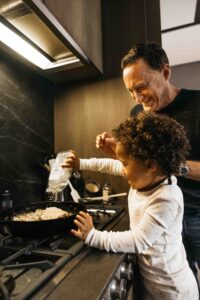 Daughter is adding extra sprinkles to the frying pan at the stove.