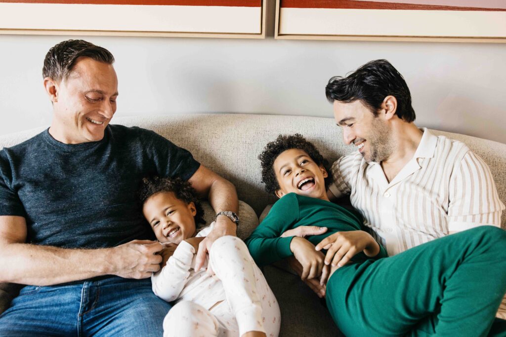 Dads are tickling their kids on the sofa.