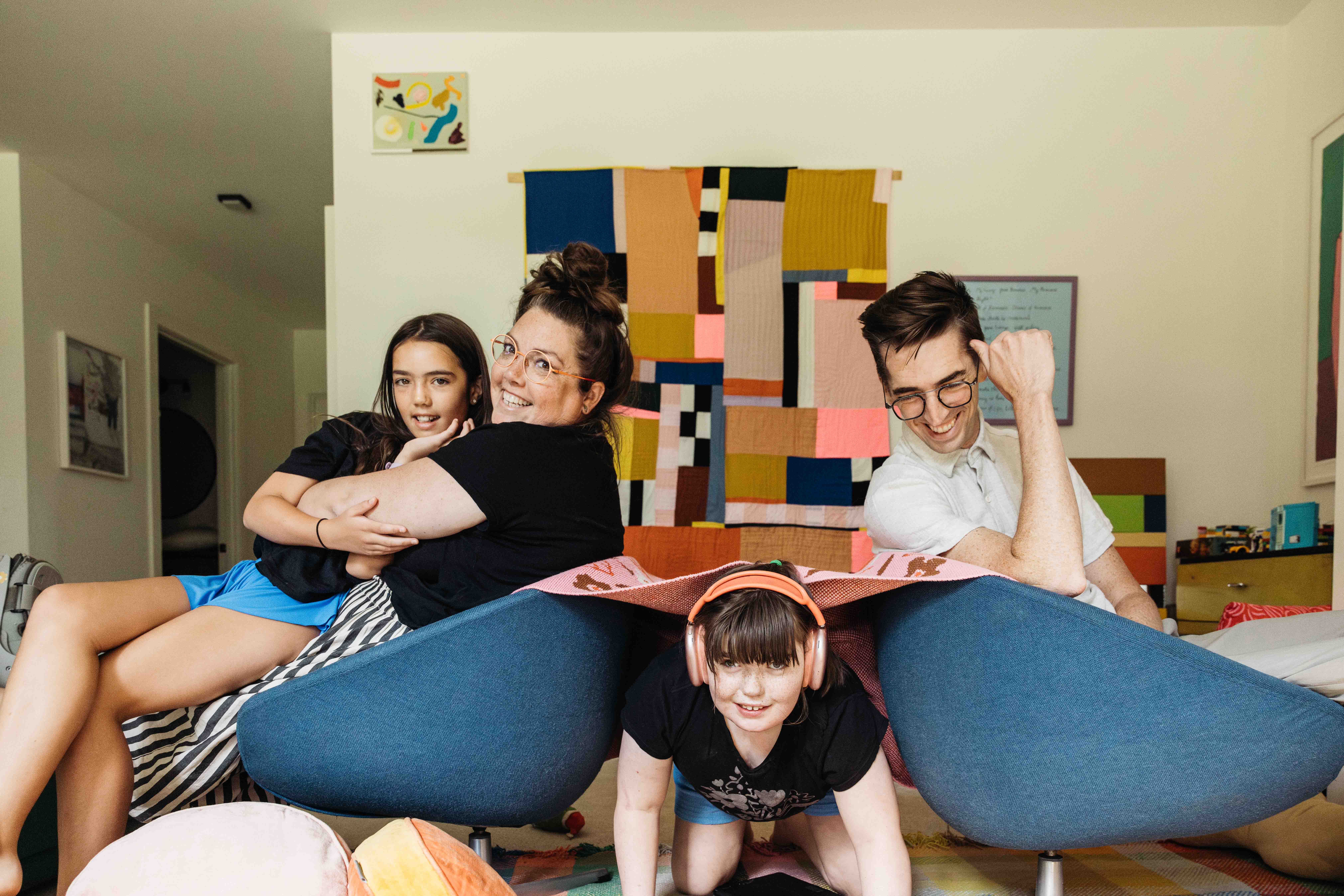 Family goofing around in the living room with their two pre-teen girls.