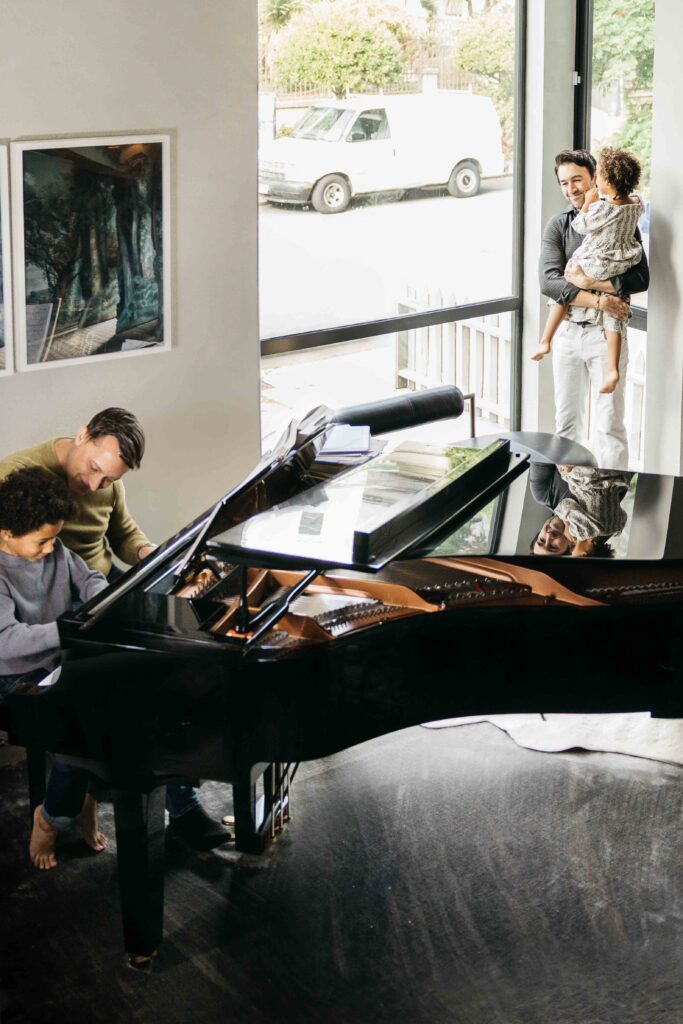 Family is playing at the piano from their living room.