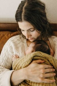 Mom tenderly holds newborn boy against her chest.