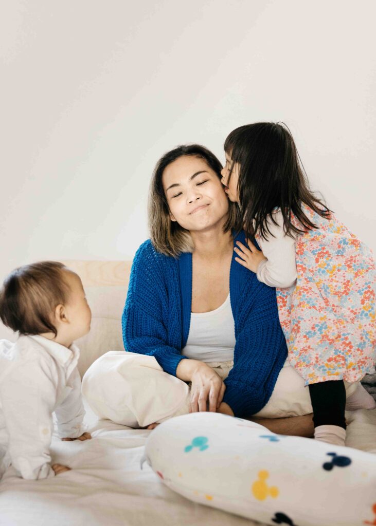 Daughter is kissing her mom on the cheek.