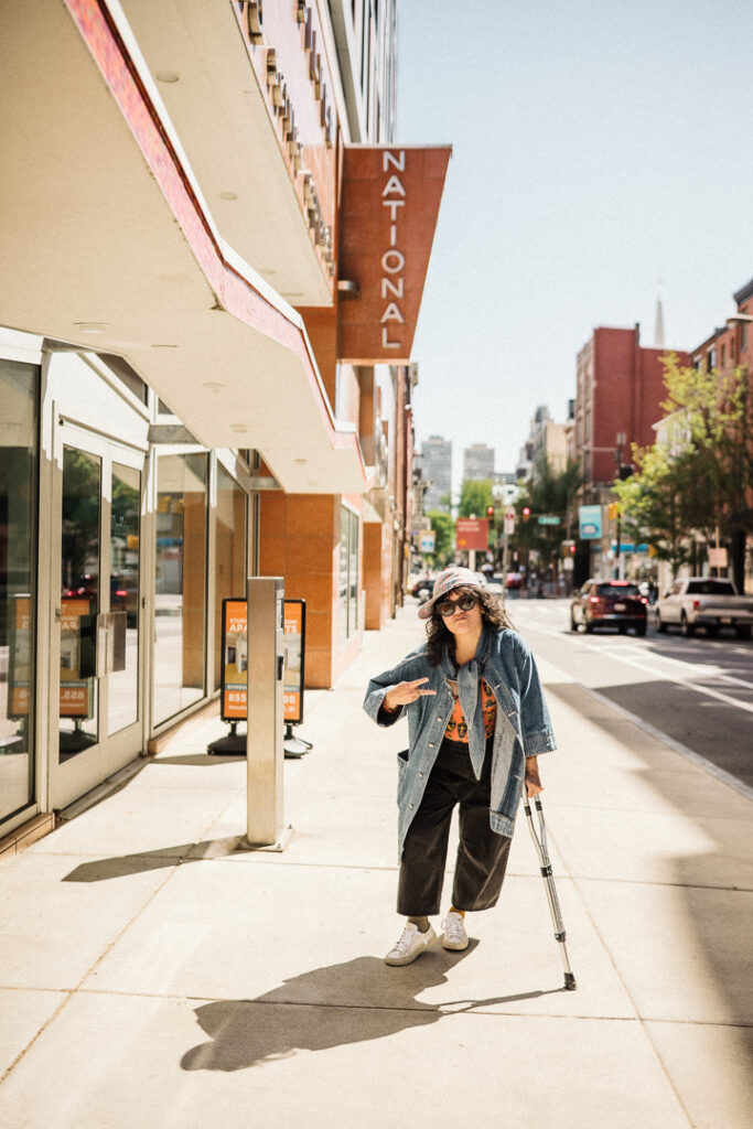Woman leaning on one crutch in downtown area with a twisted ankle.
