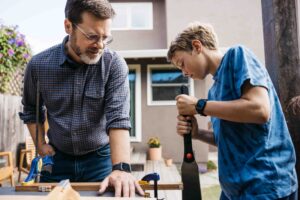Dad and son are building a project out of wood in the backyard.
